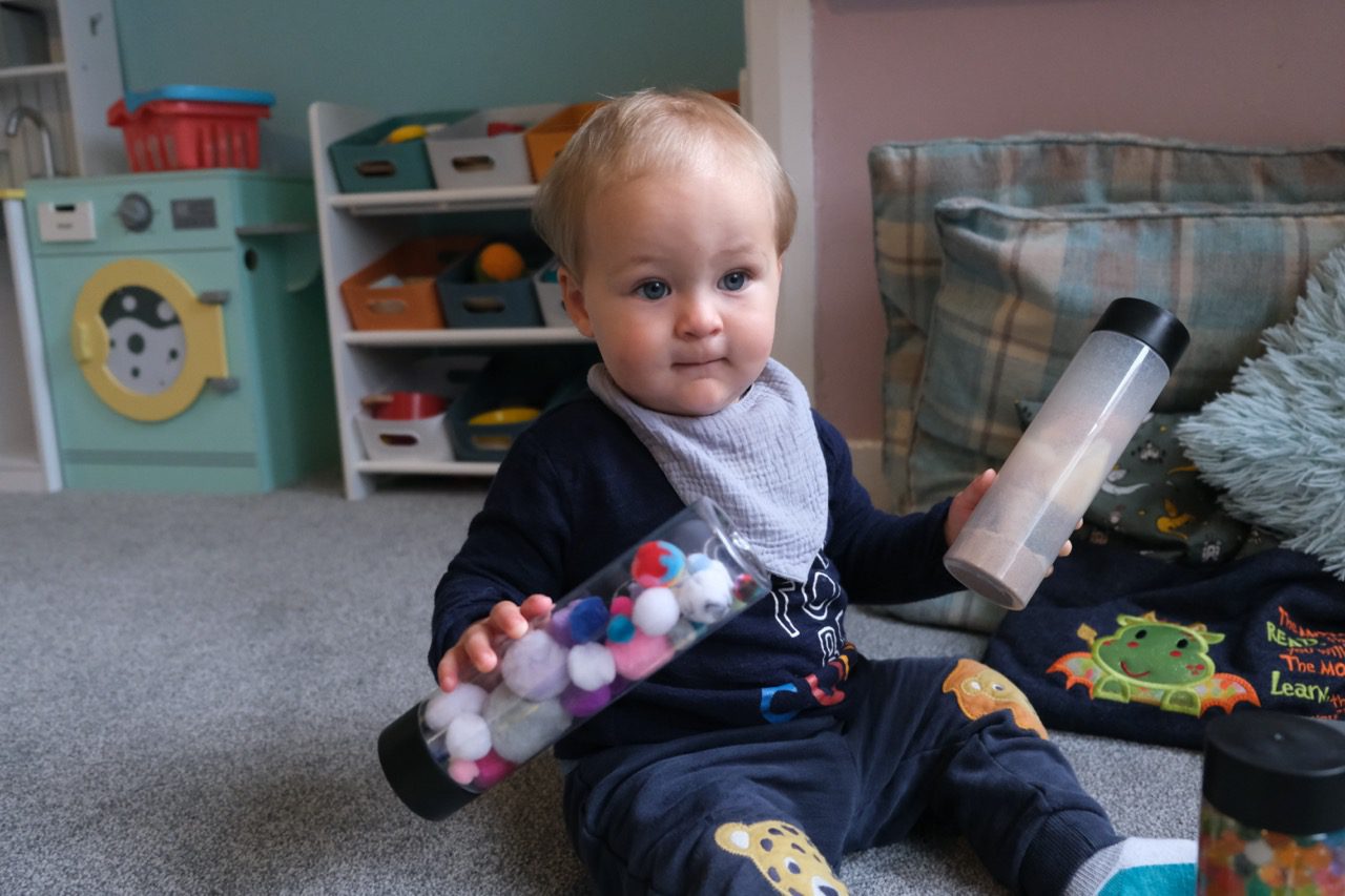 A toddler at Devon Nurseries playing with sensory tubes